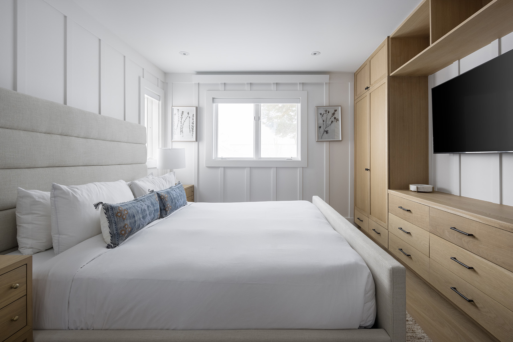 bedroom with white linens and a built-in soft wood drawers