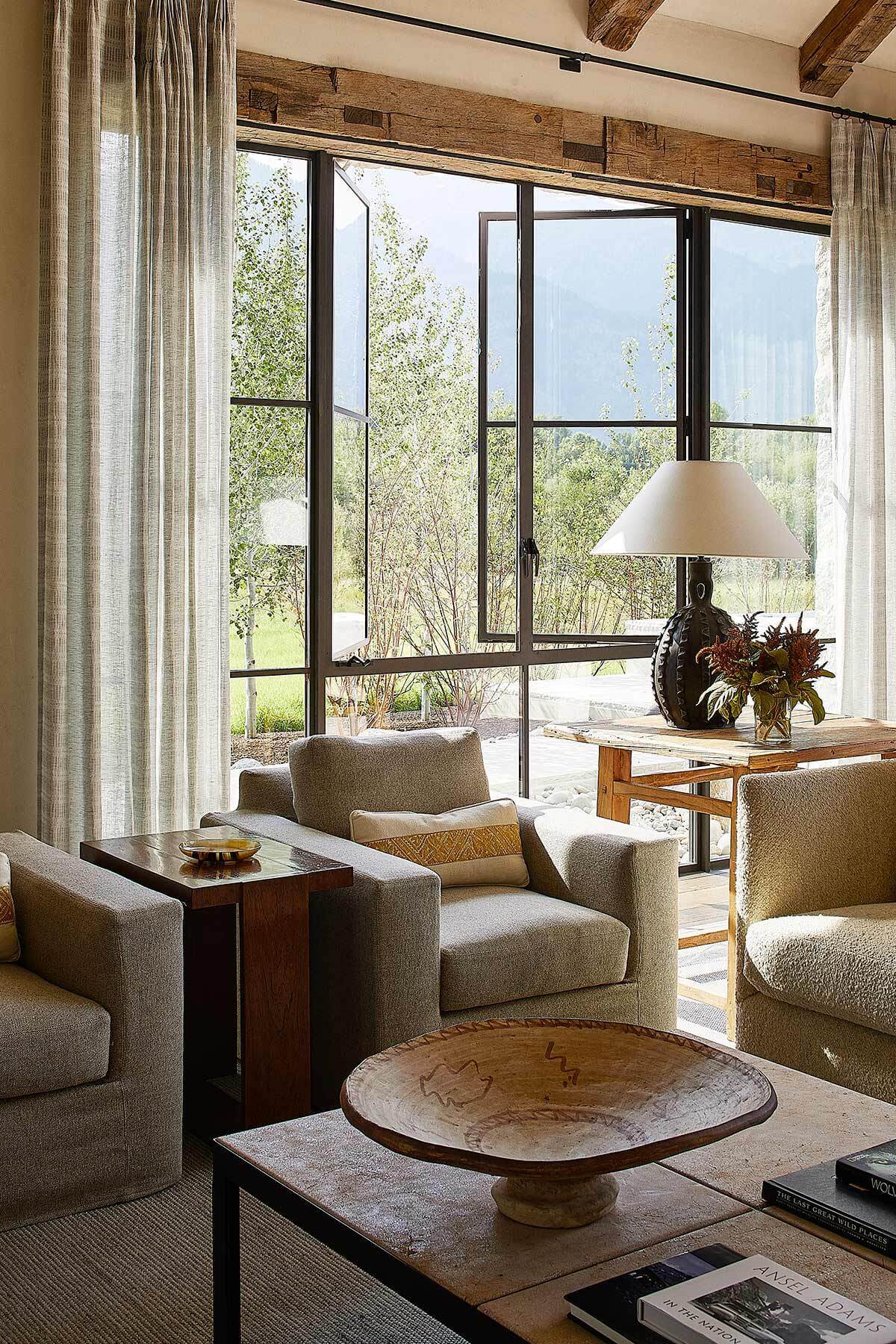 Living room with floor-to-ceiling operable windows that enhance daylighting and support natural cross-ventilation, a key feature of passive design strategy.
