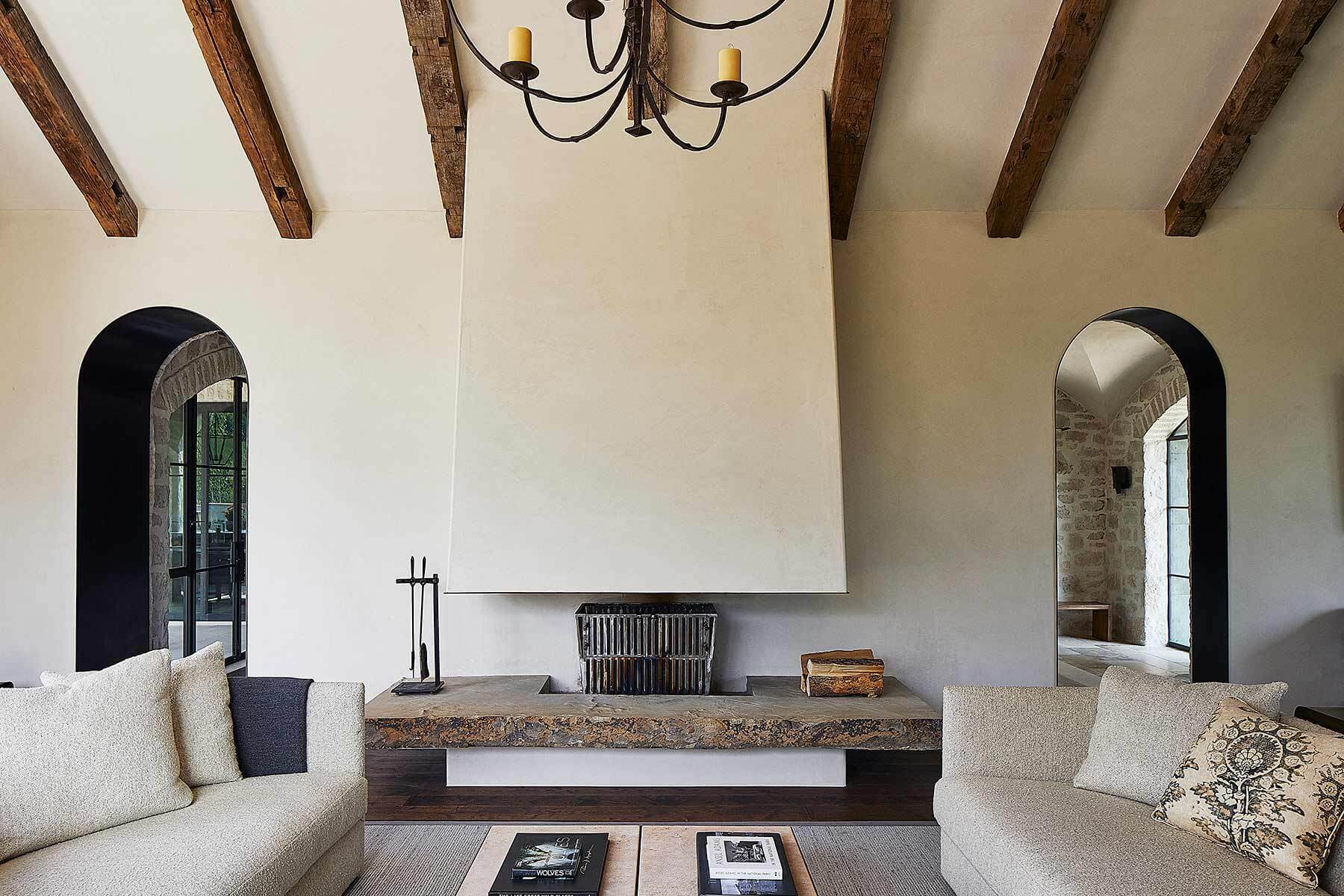 Interior of a passive house with exposed ceiling beams, thick insulated walls, and a thermal mass fireplace designed to regulate indoor temperature naturally.